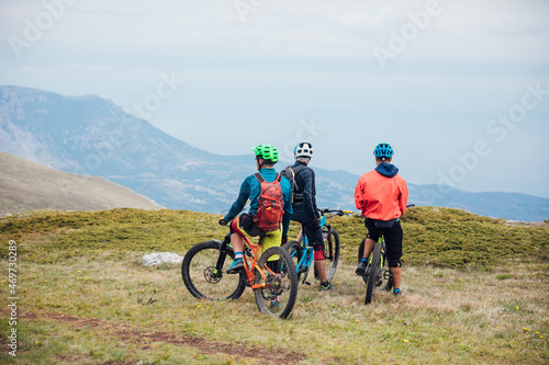 three mountain bike athletes riding in the mountains looking at the landscape