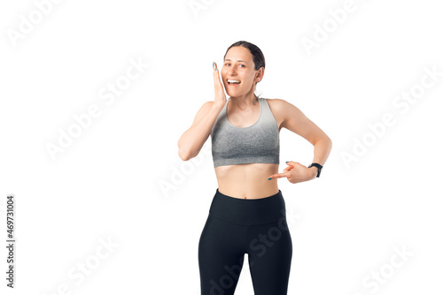 Photo of young woman, amazed of results after training,.pointing at her abs, over white background