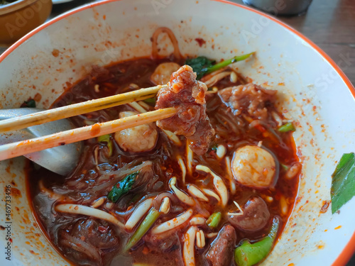 Top View of Thai boat noodles is Thailand's most famous noodles soup,Thai Boat noodles soup or Guay tiew reua ,Rice noodles thicken soup with stewed beef and beef ball. selective focus the beef