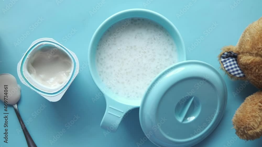 baby food in a bowl and yogurt in a container on blue background baby food in a bowl and yogurt in a container on blue background