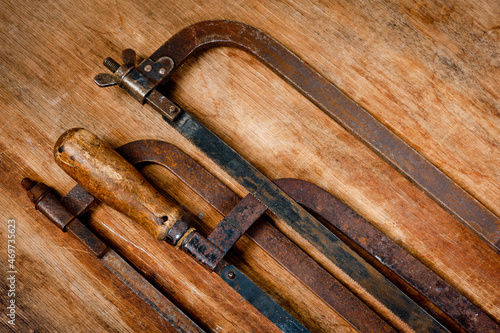 Old vintage metal hacksaws for metal shot on a wooden background.