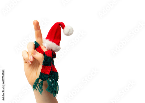 Close up view of isolated person hand show peace gesture, while wearing Christmas hat and knitted red and green scarf. Lot of copy space.