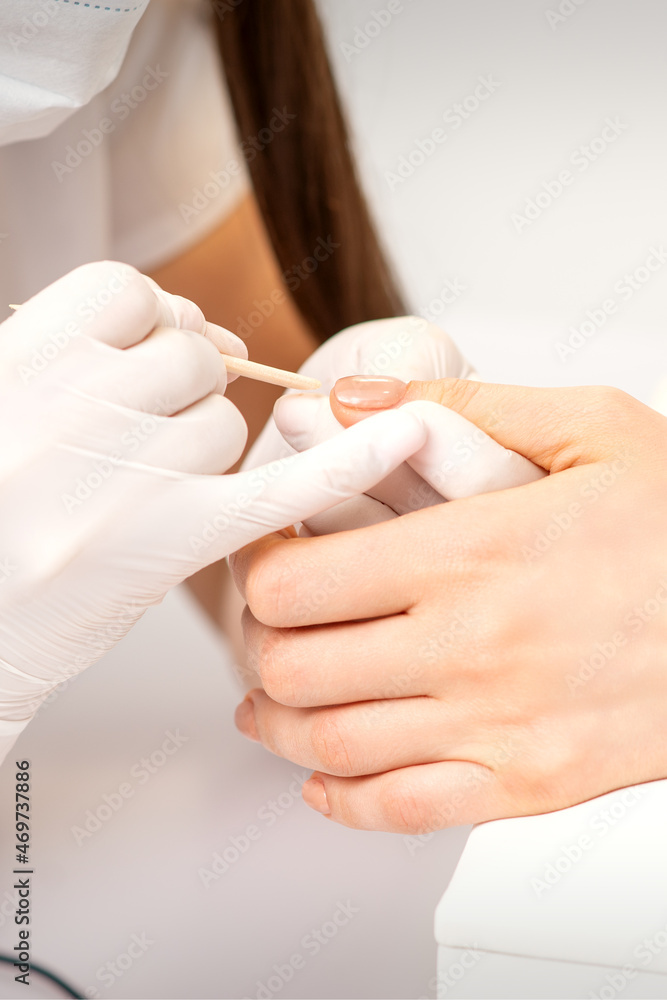 Naklejka premium Young woman receiving pink or beige nail polish in a beauty salon