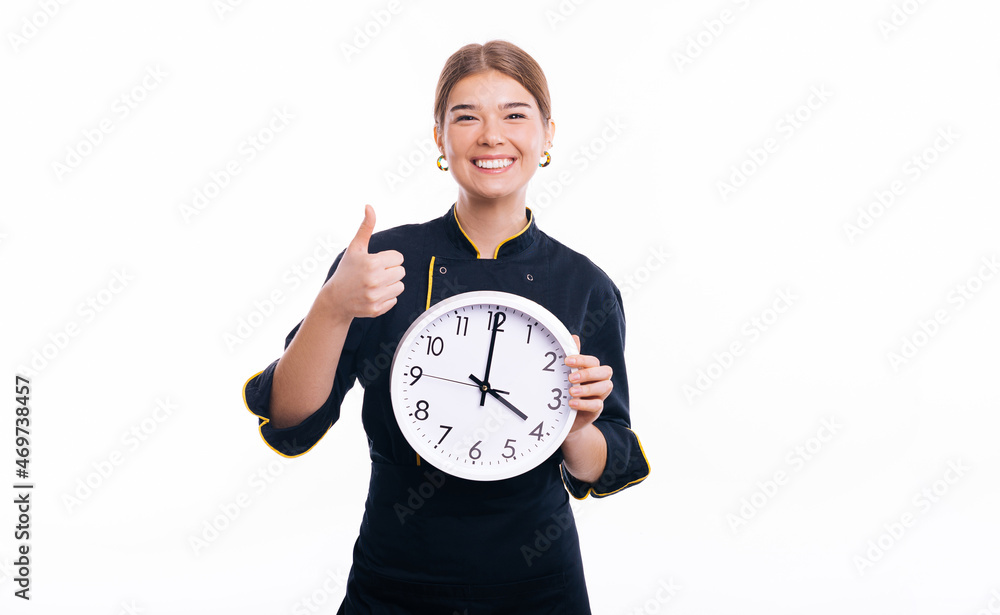 Cheerful woman chef, holding a clock and showing thumb up over white background Cheerful woman chef, holding a clock and showing thumb up over white background