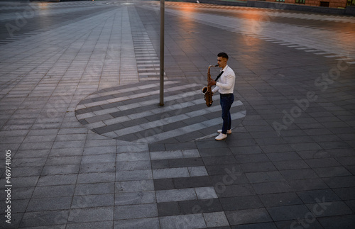Saxophonist plays the sax on street in the evening