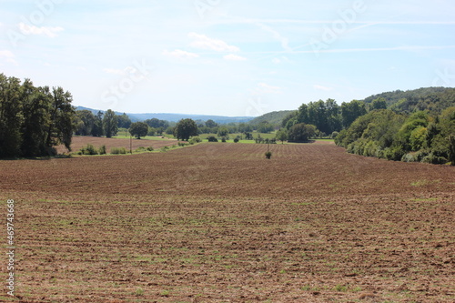 Landscape with brown plowed field in summer with mountain cliffs in France. Photo was taken on a hot day in summer. © Johan