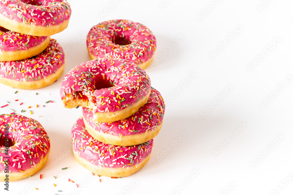 Sweet snacks - pink frosted donuts with colorful sprinkles Sweet snacks - pink frosted donuts with colorful sprinkles