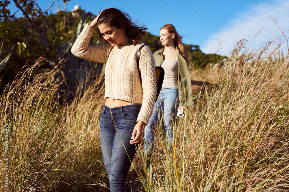 Female friends walking together in grass Female friends walking together in grass