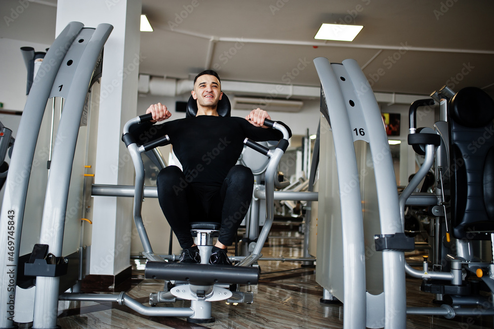 Muscular arab man training and doing workout on fitness machine in modern gym. Muscular arab man training and doing workout on fitness machine in modern gym.