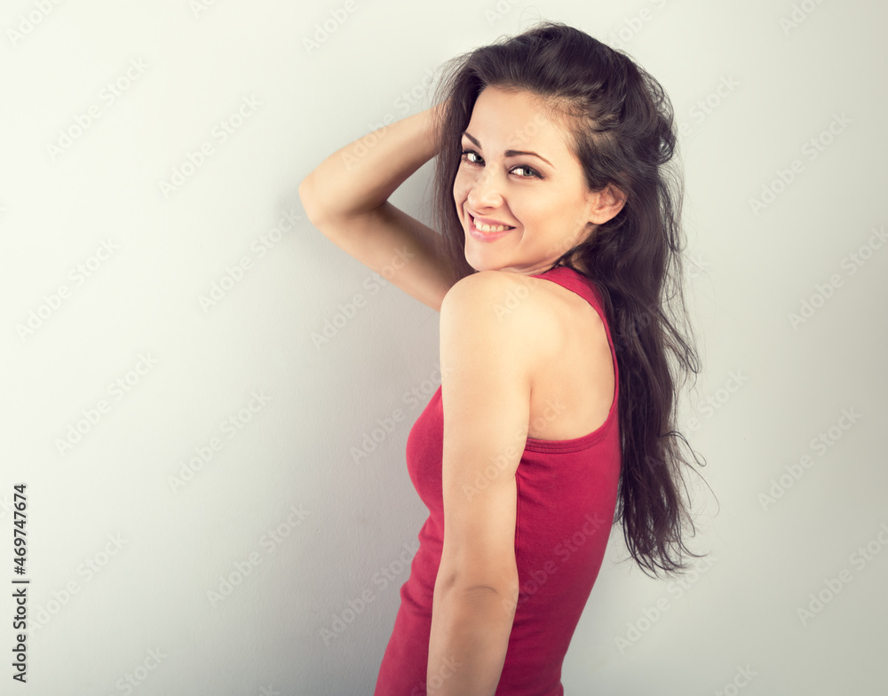 Beautiful young casual cute toothy smiling woman with long volume hairstyle in red t-shirt on blue toned color background. Closeup portrait Beautiful young casual cute toothy smiling woman with long volume hairstyle in red t-shirt on blue toned color background. Closeup portrait