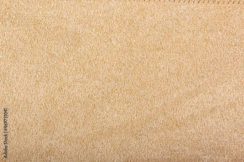 Light beige matte background of suede fabric, closeup. Beige suede soft leather as texture background