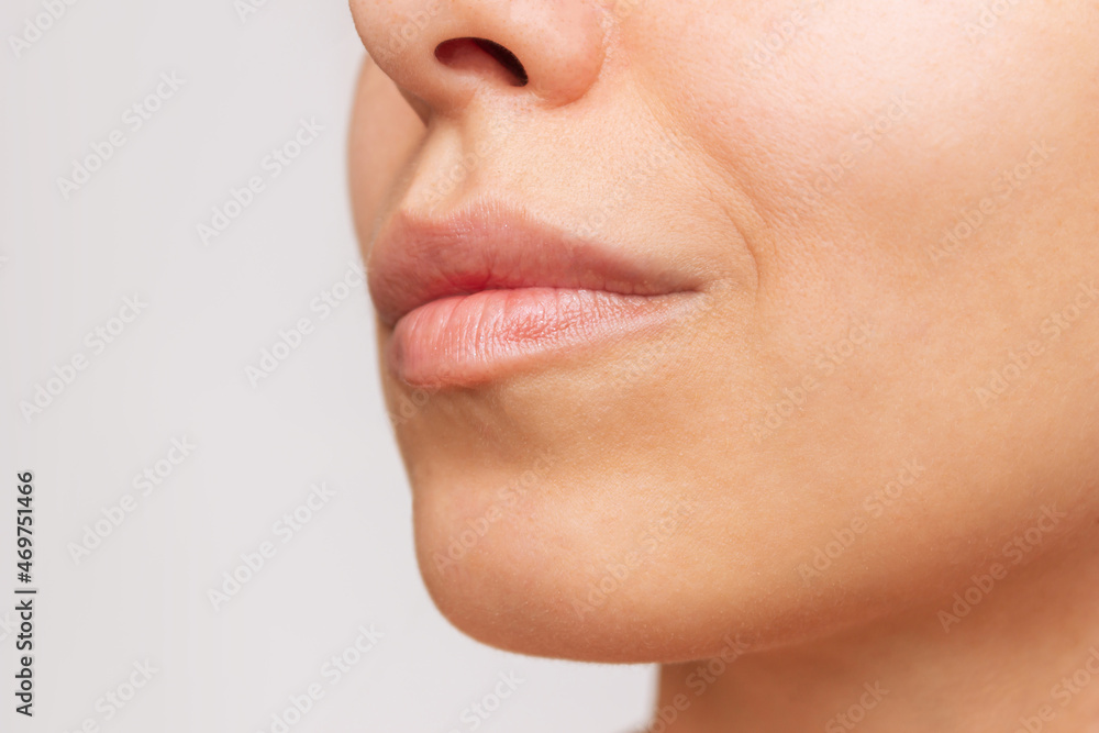 Obraz premium Cropped shot of a young caucasian pretty woman with soft smooth skin and natural full lips on a white background. Close-up