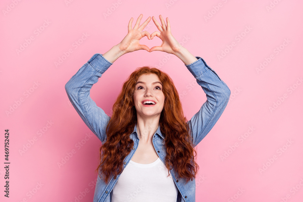 Photo of charming dreamy woman wear denim shirt showing fingers heart looking empty space smiling isolated pink color background Photo of charming dreamy woman wear denim shirt showing fingers heart looking empty space smiling isolated pink color background