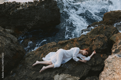 beautiful young woman lying on rocky coast with cracks on rocky surface landscape