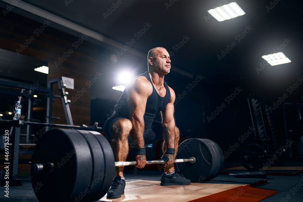 Fototapeta premium Adult bald powerlifter bodybuilder exercising deadlift barbell in gym. Powerlifting. Bodybuilding