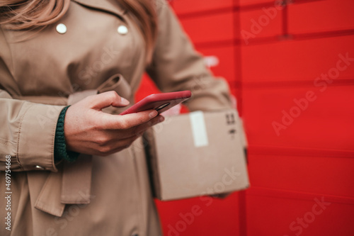 Woman using automated self service post terminal machine or locker to deposit the parcel for storage. Delivery, online ordering, food delivery