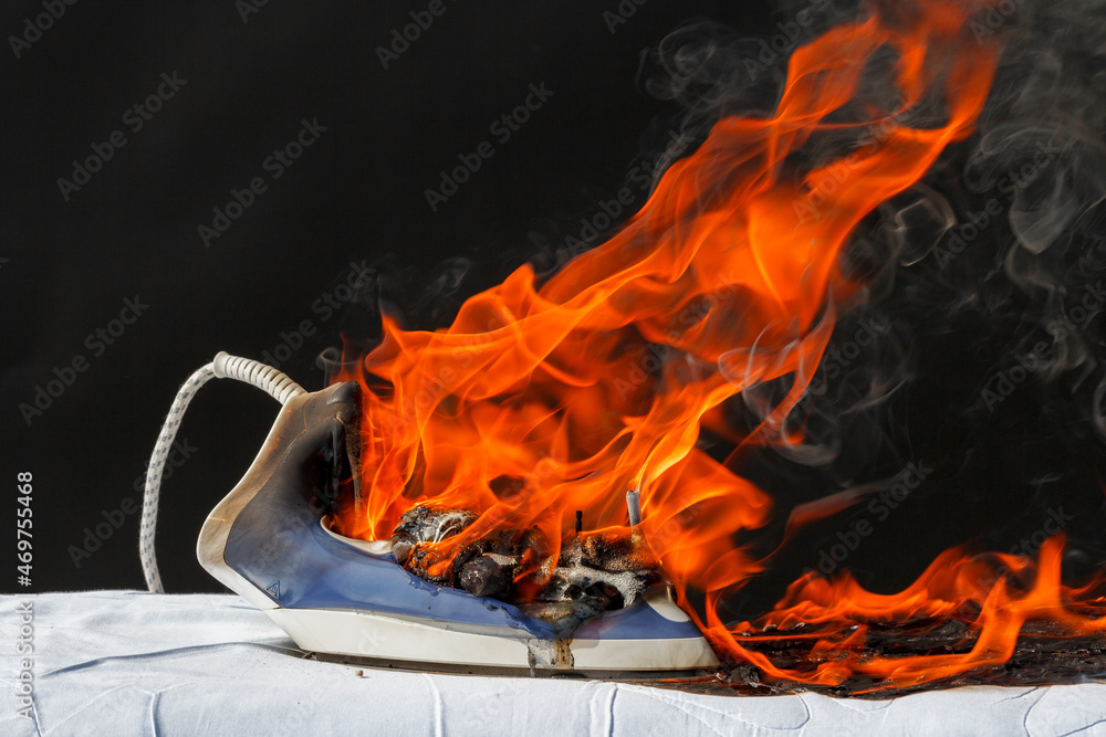 Fototapeta premium Iron on ironing board in flames fire, cause of fire