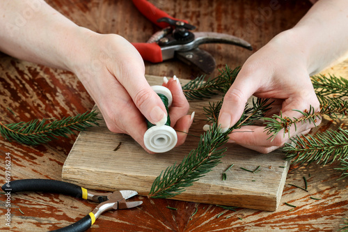 Woman shows how to make a Christmas decoration with apple, candle and branches of fir photo