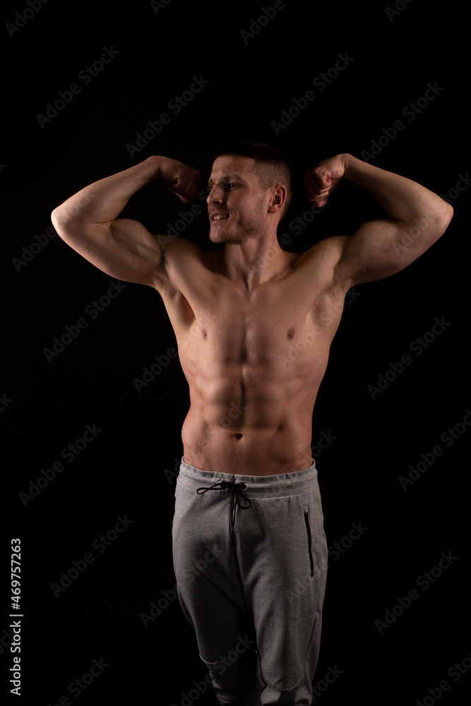 Man Showing Biceps Hands Up. Sportsman Showing Muscles. ABS, Biceps Muscles. Black Background. Topless Man Looking to Side Satanding Full Lenght Man Showing Biceps Hands Up. Sportsman Showing Muscles. ABS, Biceps Muscles. Black Background. Topless Man Looking to Side Satanding Full Lenght