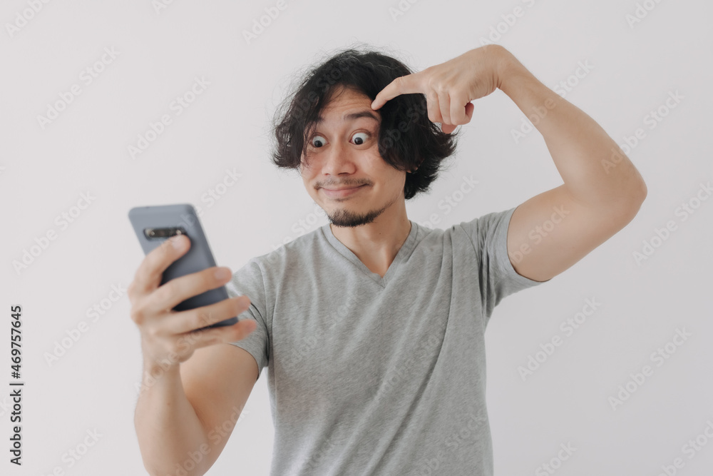 Funny and happy face of Asian man look at his smartphone on white background. Funny and happy face of Asian man look at his smartphone on white background.