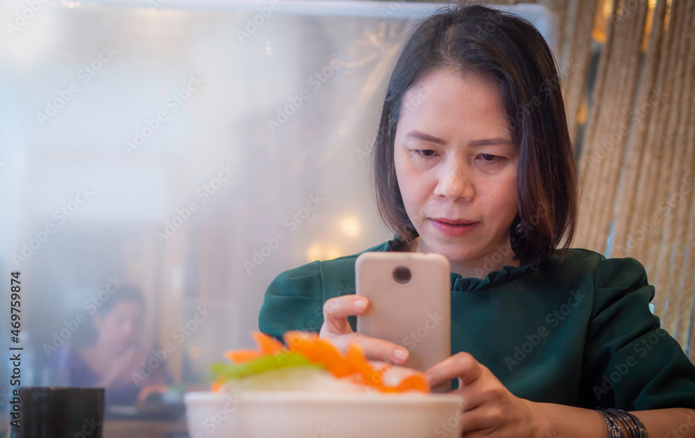 Asian woman, Thailand, black hair, good-looking personality, at a Japanese restaurant, using a smartphone to take food photos. The camera on the smartphone is custom built, unique to the brand sold.