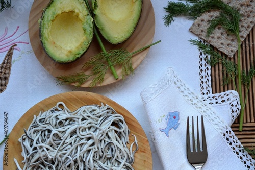 Plate of elvers (or gulas) on a tablecloth with avocados and bread