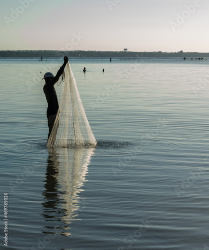 Dramatic silhouette of a fisherman casting his nets on the Caribbean bay of the Dominican Republic, after early morning sunrise.