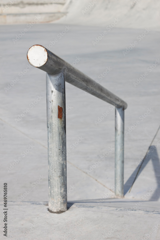 Sloped metal rail for grind tricks in an empty concrete skatepark Stock