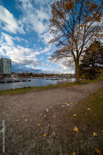 Barrie waterfront centennial park  lakeshore  path with green grass and fall colour trees   blue sky with broken clouds 