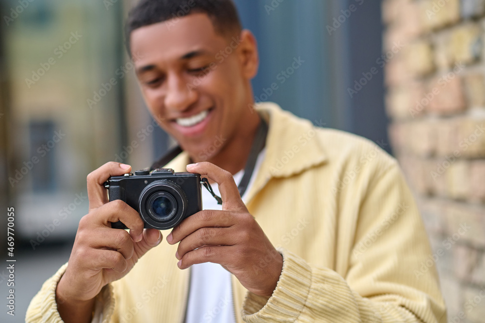 Positive photographer with camera in hands looking happy