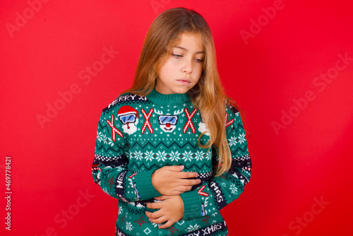 Billede på lærred little kid girl wearing knitted sweater christmas over red background suffering from strong stomachache