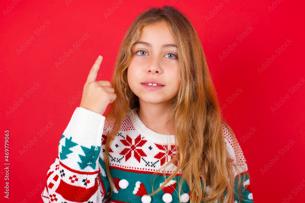 little kid girl wearing knitted sweater christmas over red background smiling and looking friendly, showing number one or first with hand forward, counting down little kid girl wearing knitted sweater christmas over red background smiling and looking friendly, showing number one or first with hand forward, counting down