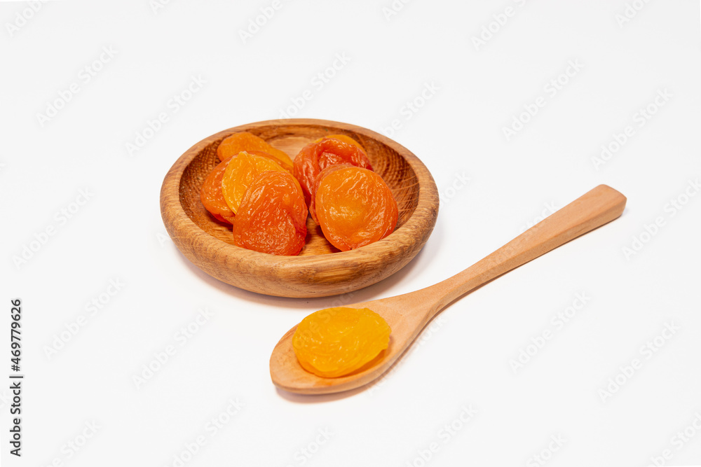 Dried apricots in a wooden saucer and a wooden spoon. Dried apricots in a wooden saucer and a wooden spoon.