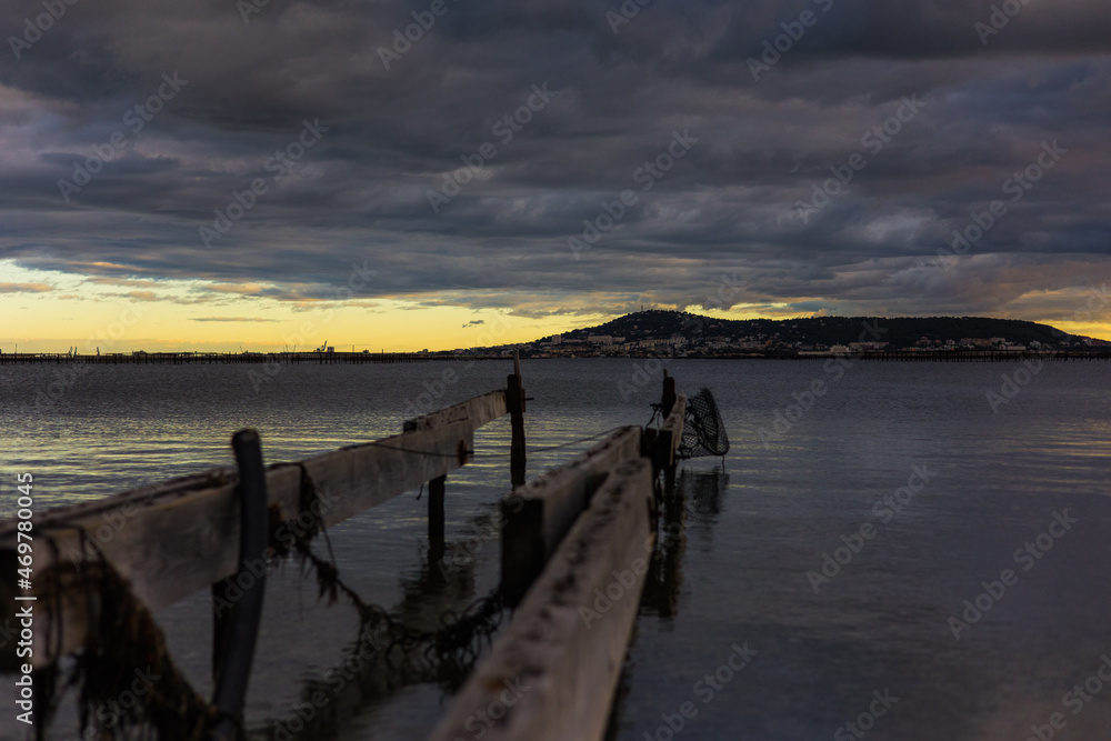 Fototapeta premium Vue sur le Mont Saint-Clair de Sète au coucher de soleil par temps tempétueux depuis les berges de l’étang de Thau à Bouzigues (Occitanie, France) 