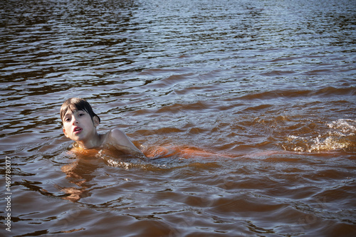 Boy swimming in water with small waves with wet hair