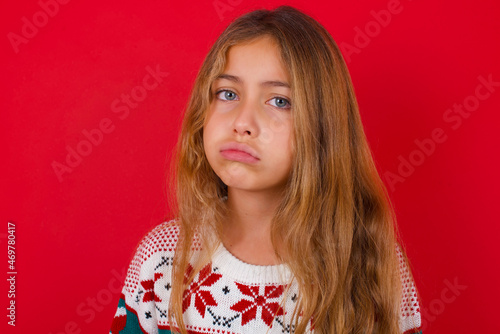 little kid girl wearing knitted sweater christmas over red background depressed and worry for distress, crying angry and afraid. Sad expression.