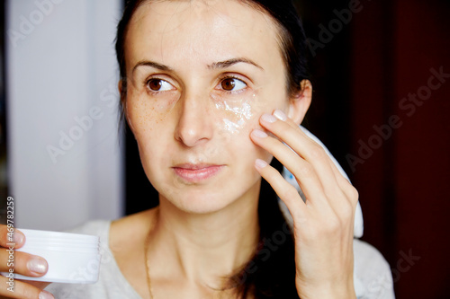 Young caucasian woman uses a transparent patches with sparkles. Dermatology multiuse cosmetics, multitasking beauty. Scinimalism concept, polytasking functions. Macro, close up face photography. photo