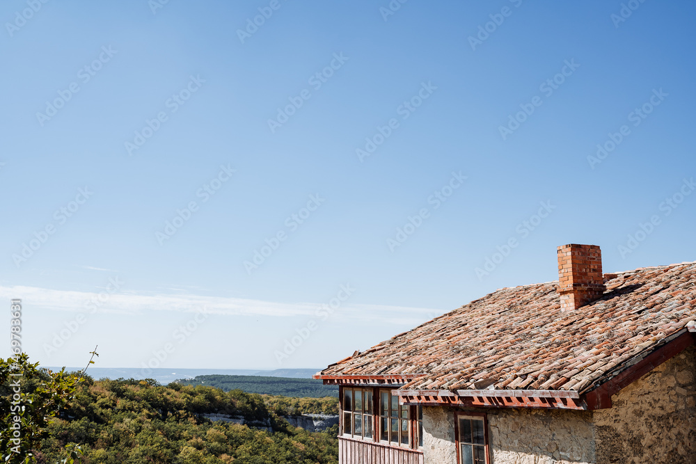 Old house with a tiled roof in the mountains. Clear endless sky, view of the green plains. Rest at the resort. Antique house. Old house with a tiled roof in the mountains. Clear endless sky, view of the green plains. Rest at the resort. Antique house.