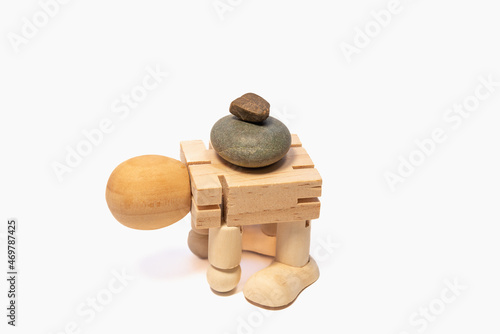 A wooden man carries large stones on his back, hard work of a man. photo