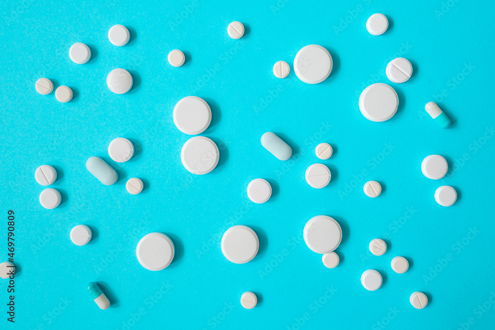 White medicines or pills on blue background for a design on a medical topic White medicines or pills on blue background for a design on a medical topic