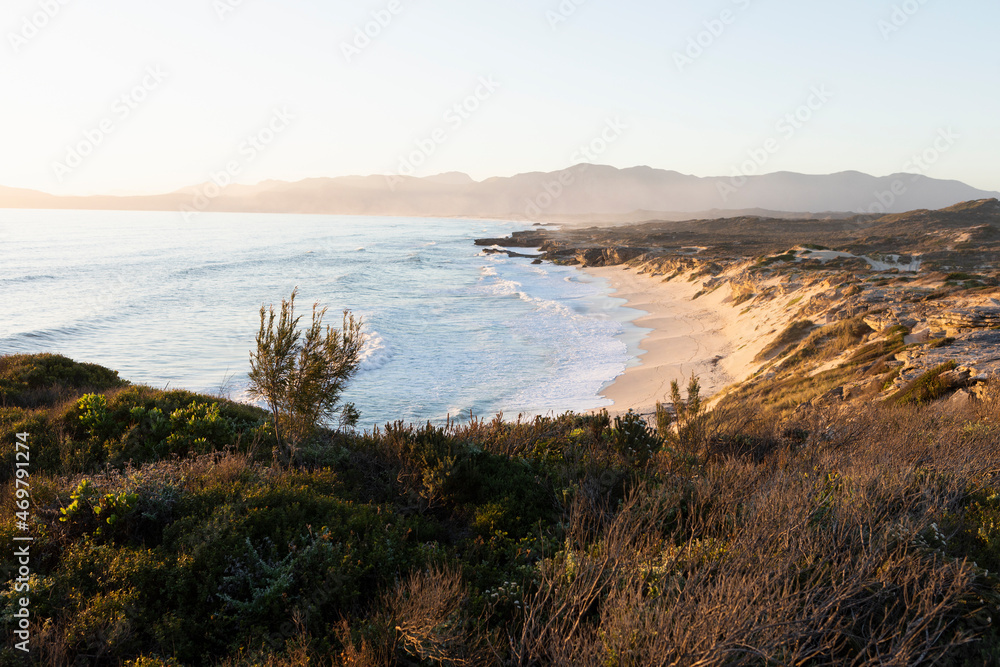 View from the cliffs over the sandy beach and waves breaking on shore. View from the cliffs over the sandy beach and waves breaking on shore.