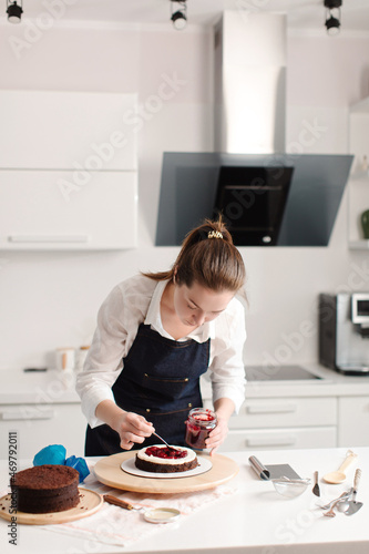 Woman making chocolate cake in kitchen, close-up. Lays berries. Cake making process, Selective focus. High quality photo