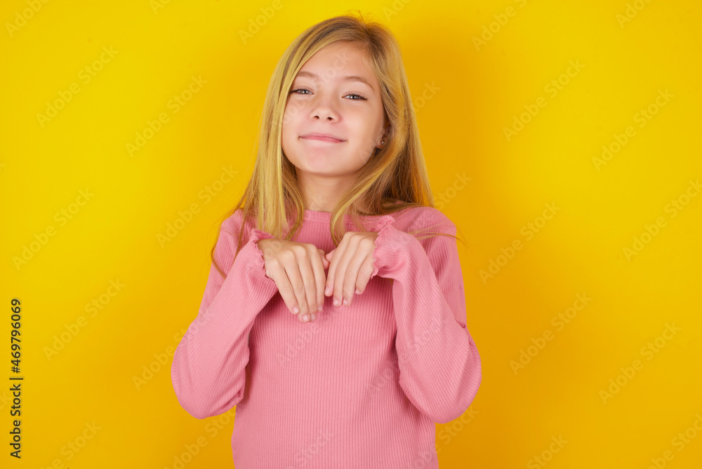 caucasian little kid girl wearing long sleeve shirt over yellow background makes bunny paws and looks with innocent expression plays with her little kid caucasian little kid girl wearing long sleeve shirt over yellow background makes bunny paws and looks with innocent expression plays with her little kid