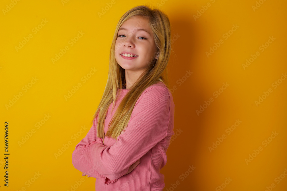 Portrait of caucasian little kid girl wearing long sleeve shirt over yellow background standing with folded arms and smiling Portrait of caucasian little kid girl wearing long sleeve shirt over yellow background standing with folded arms and smiling