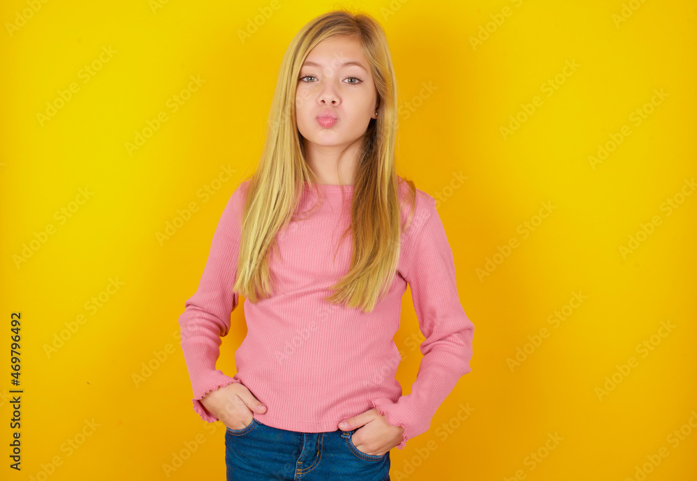 Portrait of lovely funny caucasian little kid girl wearing long sleeve shirt over yellow background sending air kiss Portrait of lovely funny caucasian little kid girl wearing long sleeve shirt over yellow background sending air kiss