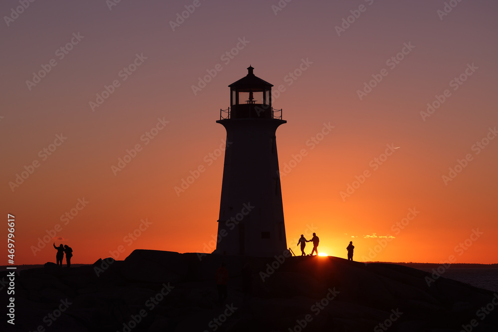 Silhouette shot of a couple and the  lighthouse on a beautiful sunset full of red and orange sky. 
Peggy's Cove Lighthouse, Halifax, Nova Scotia, Canada
