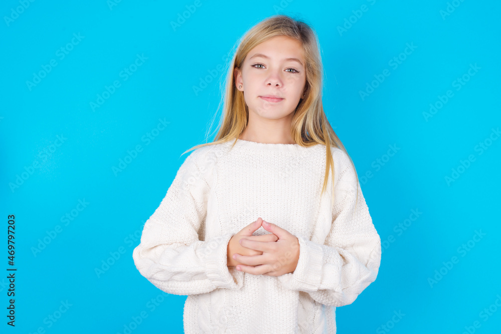 Business Concept - Portrait of caucasian little kid girl wearing wool jersey over blue background holding hands with confident face. Business Concept - Portrait of caucasian little kid girl wearing wool jersey over blue background holding hands with confident face.