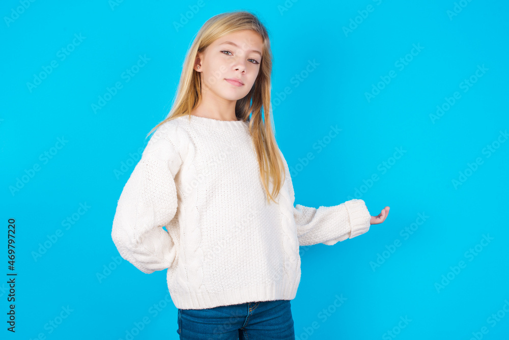 Portrait of caucasian little kid girl wearing wool jersey over blue background with arm out in a welcoming gesture. Portrait of caucasian little kid girl wearing wool jersey over blue background with arm out in a welcoming gesture.