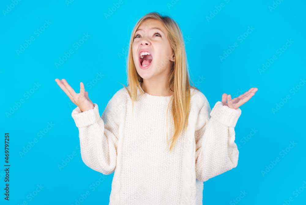 caucasian little kid girl wearing wool jersey over blue background crying and screaming. Human emotions, facial expression concept. Screaming, hate, rage. caucasian little kid girl wearing wool jersey over blue background crying and screaming. Human emotions, facial expression concept. Screaming, hate, rage.