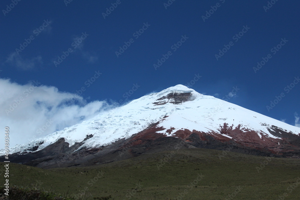 Snowy active volcano with clouds 